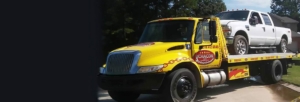 Yellow Chacon Towing Flatbed Tow Truck With a white truck on the bed in San Antonio